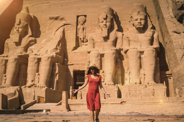 a young tourist in a red dress leaving the abu simbel temple in southern egypt in nubia next to lake