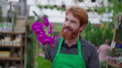 Wall Mural - Young man entrepreneur of Flower Shop walking in Horticulture store aisle while holding flower. A male person carrying product for client delivery