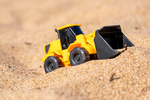 A Yellow Toy Excavator On The Sand Beach