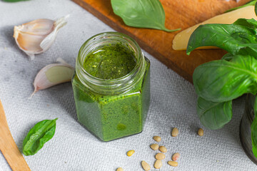 Wall Mural - Pesto sauce in a glass jar on the table. Basil