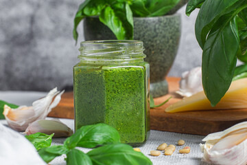 Wall Mural - Pesto sauce in a glass jar on the table. Basil