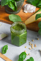 Wall Mural - Pesto sauce in a glass jar on the table. Basil