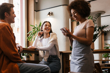 Wall Mural - Smiling waitress serving couple in cafe