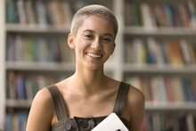 Happy Pretty Stylish Short Haired Student Girl With Teeth Brackets Standing In Campus Library, Looking At Camera, Smiling, Laughing, Showing Braces. Head Shot Portrait