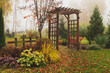 wooden rustic archway in autumn natural garden. Foggy october day