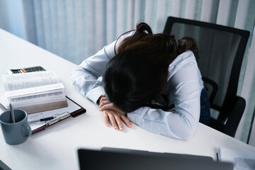 Alone Working Late. Asian business woman at workplace in office  laid her head down on the table fell asleep in front of laptop