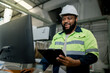 © Montri - Two professional engineer,worker,technician use clipboard discuss work, walk in steel metal manufacture factory plant industry. Black African American man and woman wear hard hat check quality
