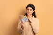 thoughtful caucasian woman with brazil banknotes currency in beige studio background. finance, investment, offer, loan concept. 