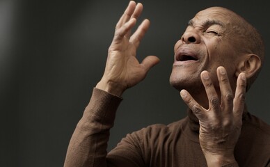 man praying to god with hands together with depression on grey background stock photo	