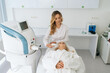© dikushin - Portrait of female beautician making photo rejuvenation procedures for client in aesthetic medicine clinic with modern light interior. Concept of non-surgery cosmetology, professional skincare
