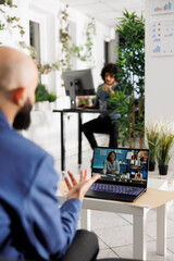 Wall Mural - Executive in startup company leading virtual meeting with business partners on laptop screen in coworking space. Entrepreneur attending video call with remote managers in office
