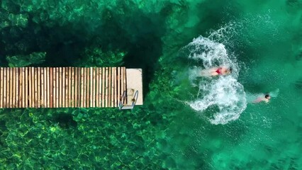 Wall Mural - a carefree couple jumps into the azure sea. aerial view. a vacation in the summertime. young and ene