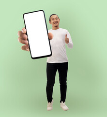 Asian man looking to camera, smiling and showing empty blank white copy space phone mock up template