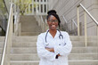 © Tetra Images - Portrait of smiling female doctor on steps in city