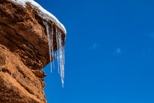 Icicles Hanging From Rock Against Blue Sky