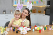 © New Africa - Mother and her cute son painting Easter eggs at table in kitchen