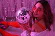 © New Africa - Beautiful woman in stylish outfit with disco ball at party indoors, toned in pink