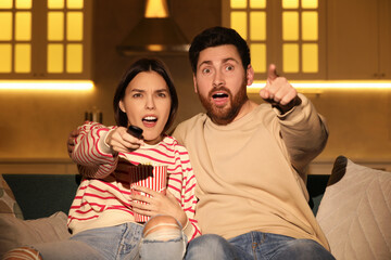 Canvas Print - Emotional couple watching TV with popcorn on sofa