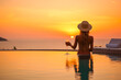 © MVProductions - Woman watching the sunset with a cocktail in an infinity pool, showcasing luxury lifestyle, generative ai