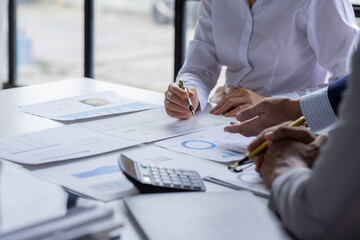 Group of confident business people point to graphs and charts to analyze market data, balance sheet, account, net profit to plan new sales strategies to increase production capacity.	