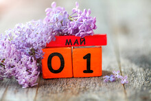 Wooden Calendar With Russian Text May 1 And A Bouquet Of Lilacs On A Wooden Background.Spring Day, Empty Space For Text. International Workers' Day