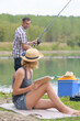 © auremar - lady reading book while man fishes in lake