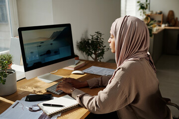 Aufkleber - Young creative female webdesigner sitting by workplace in front of computer monitor and typing while working over new website