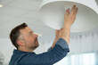 man installing a bulb in living room at home