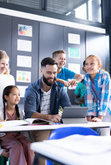 Sticker - Vertical of happy diverse elementary children and male teacher using tablet in class, copy space