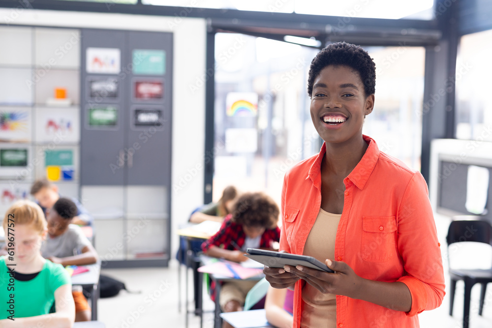 Portrait of happy african american female teacher holding tablet in ...