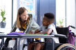 © WavebreakMediaMicro - Happy, diverse schoolgirl and schoolboy in wheelchair working together at desk in class