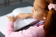 Elevated view of blind, biracial schoolgirl at desk reading braille in class with copy space