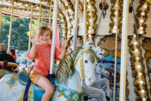 Happy Positive Preschool Girl Having A Ride On The Old Vintage Merry-go-round In City Of St Malo France. Smiling Child On A Horse.