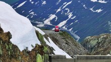 Isolated Red Camper Van Stopped At Viewpoint Of Winding Mountainous Road In Grimsel Pass, Switzerland. Parallax Pedestal Up And Tilt Down