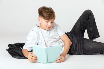 Handsome teenage school boy reading book while lying on the floor. Back to school concept