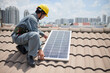 © DragonImages - Cropped image of worker installing solar panels on roof of residential building