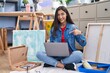 © Krakenimages.com - Young teenager girl sitting at art studio using laptop smiling happy pointing with hand and finger