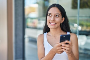 Wall Mural - Young beautiful hispanic woman smiling confident using smartphone at street