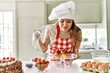 © Krakenimages.com - Young beautiful hispanic woman smiling confident smelling cupcakes at the kitchen