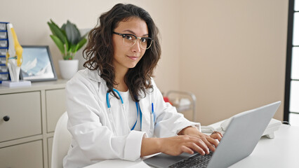 Canvas Print - Young beautiful hispanic woman doctor using laptop working at clinic