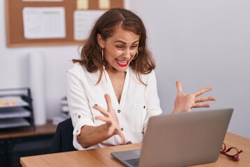 Poster - Young beautiful hispanic woman business worker using laptop with surprise expression at office