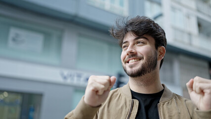 Poster - Young hispanic man smiling confident standing with winner expression at street