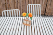 Outdoors white steel table and chairs on a wooden terrace in summer
