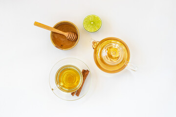 Wall Mural - Top view of a cup of tea with ginger root, lime, cinnamon and teapot on white background. Health drink concept..