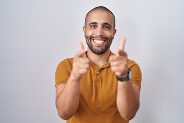 Poster - Hispanic man with beard standing over white background pointing fingers to camera with happy and funny face. good energy and vibes.