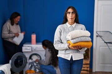 Canvas Print - Three women doing laundry at home making fish face with mouth and squinting eyes, crazy and comical.