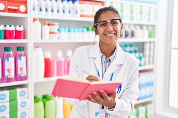 Canvas Print - Young beautiful hispanic woman pharmacist writing on document at pharmacy