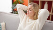 © Krakenimages.com - Young blonde woman relaxed with hands on head sitting on sofa at home