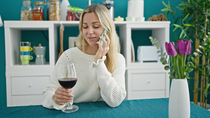 Poster - Young blonde woman drinking glass of wine talking on smartphone at dinning room