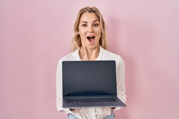 Sticker - Young caucasian woman holding laptop showing screen celebrating crazy and amazed for success with open eyes screaming excited.